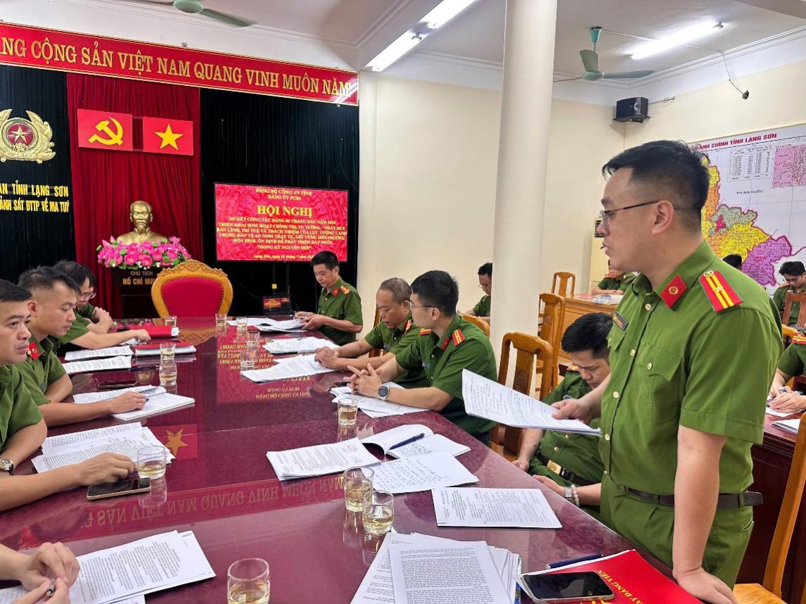 The image depicts a gathering of military personnel in a room, with documents and a tablecloth on a table, under a red banner with Vietnamese national symbols and slogans.

AI-generated content may be incorrect.