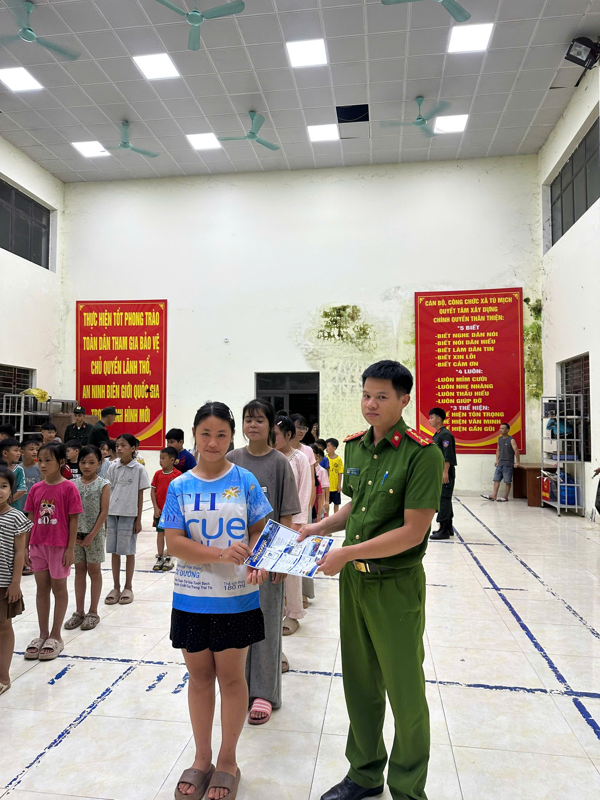 A person in a uniform holding a paper with a child in a room with people

AI-generated content may be incorrect.