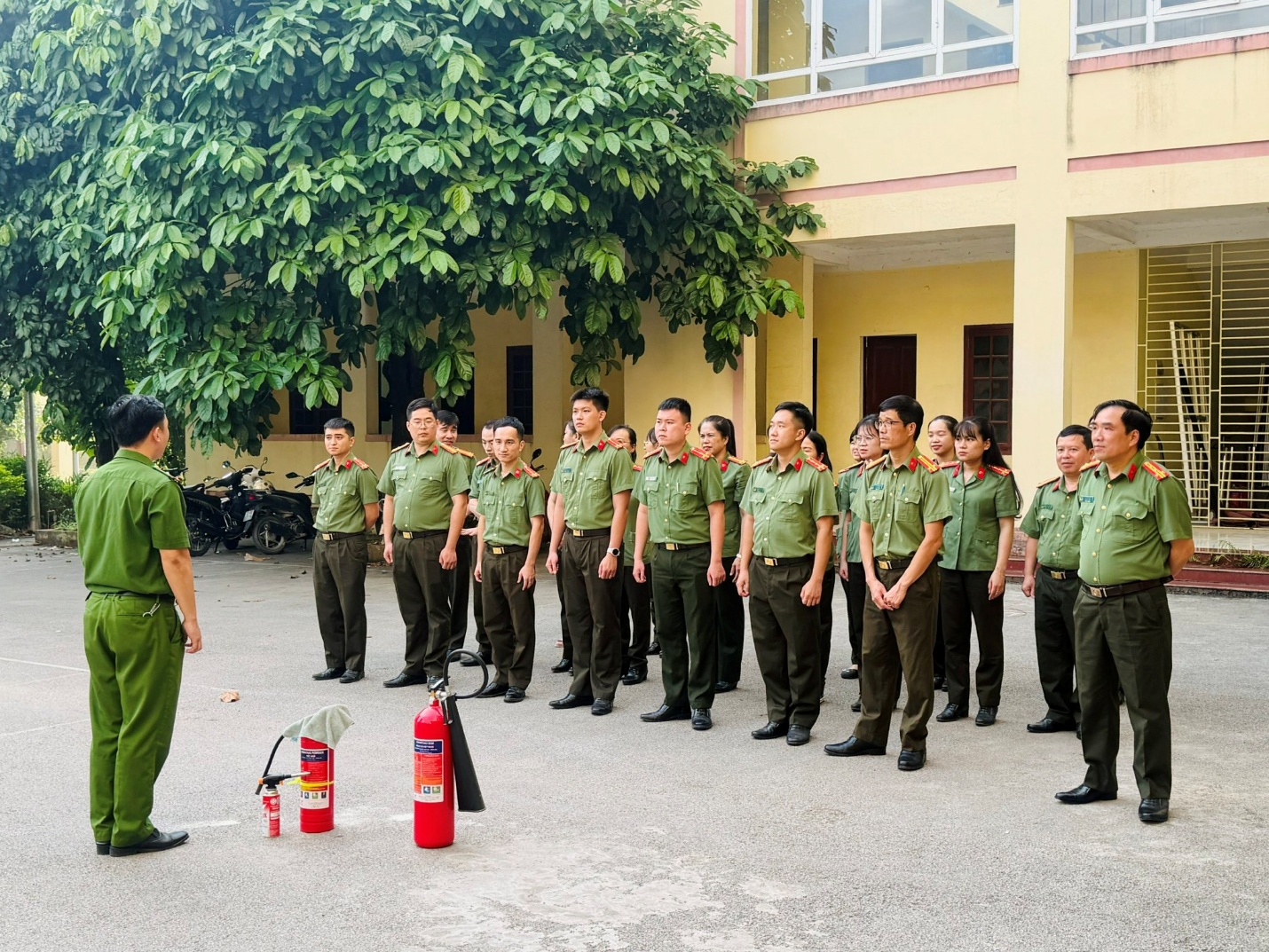 A group of military personnel in uniform stands in front of a red fuel canister outside a building.

AI-generated content may be incorrect.